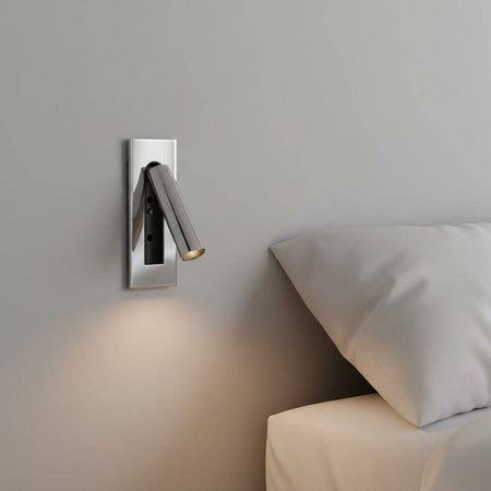 Polished chrome recessed LED reading wall lamp mounted on the wall next to a bed in a modern bedroom