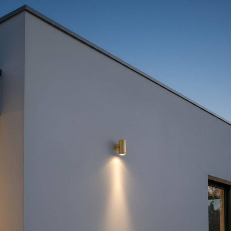 exterior brass wall light mounted on the exterior white wall of a modern home 