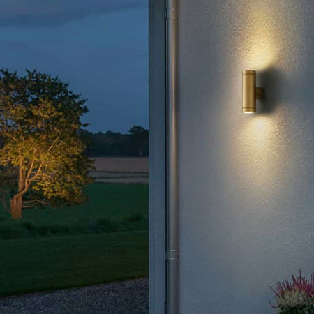 brass up down outdoor wall light mounted on a white textured wall outside a house