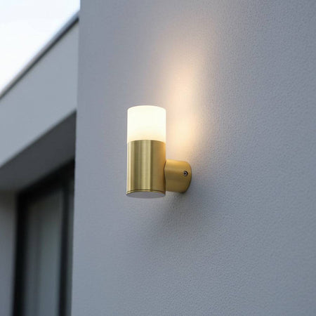 brass outdoor wall light mounted on a textured white wall outside of a modern house 