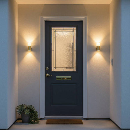 brass outdoor wall light mounted either side of the blue front door of a house