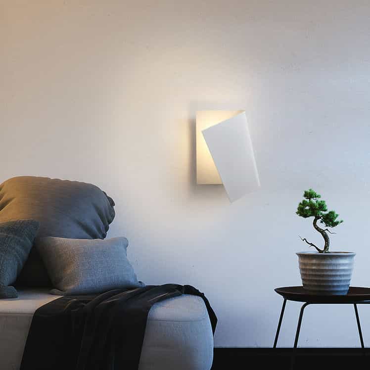 White indoor wall sconce mounted vertically showing a sofa table and plant