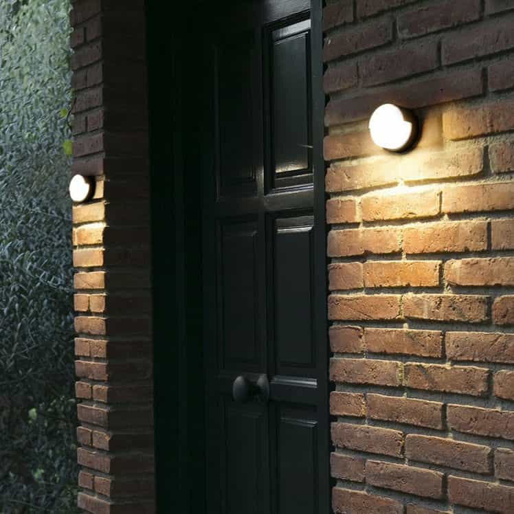 Black LED exterior wall light fitted either side of a front door on a brick wall 