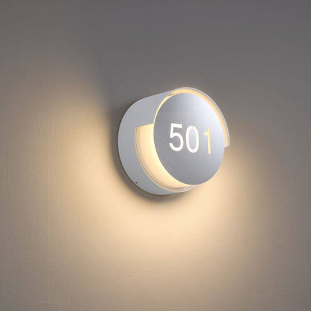Illuminated hotel room number sign mounted on a white wall 
