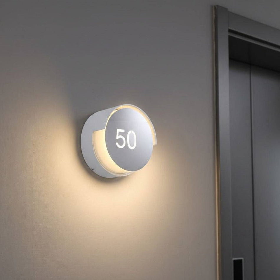white LED house number sign mounted on the wall next to  front door