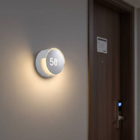 illuminated hotel room number sign mounted next to a hotel door 