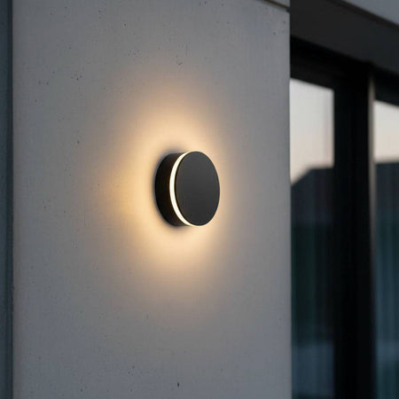 black LED outdoor wall lamp mounted on a concrete wall outside of a modern house 