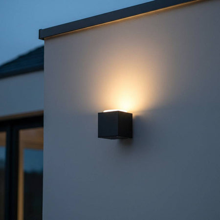 black outdoor uplighter wall light mounted on the white external wall of a modern home 