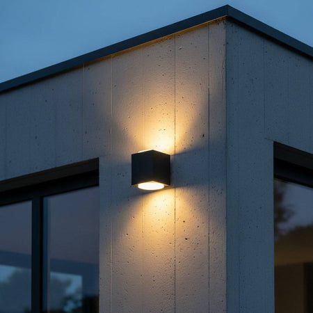black outdoor up and down light mounted on the concrete wall outside a modern house 