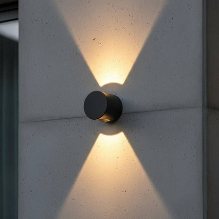 black outdoor up down wall light installed on a concrete wall outside a modern home