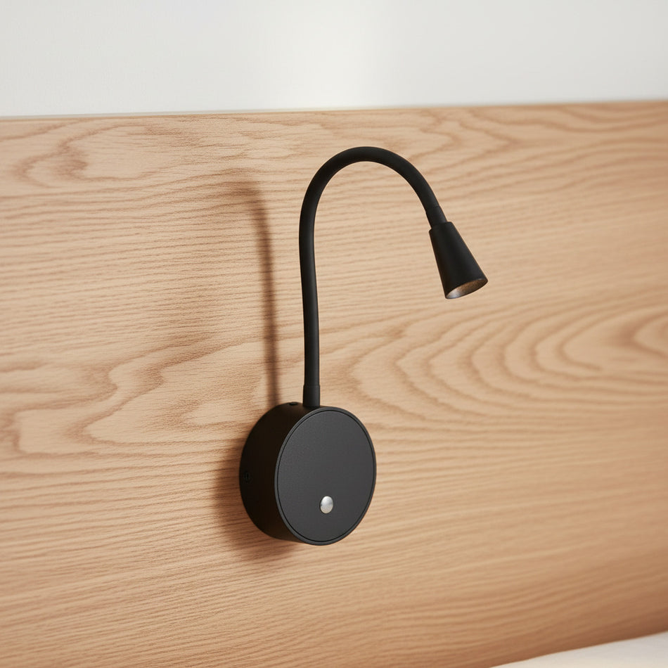 black flexible LED reading light with USB ports mounted on a wooden bed headboard