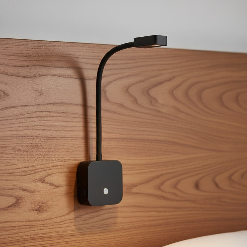 flexible black bedroom reading light with USB ports mounted on a wooden headboard