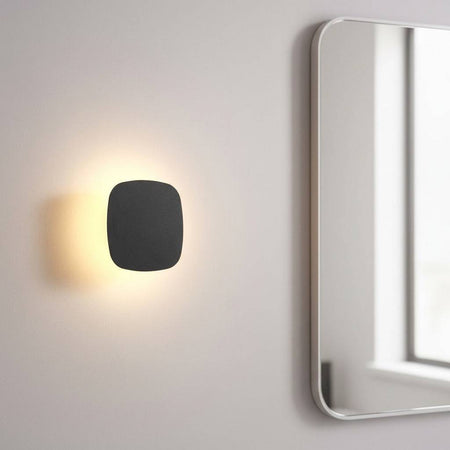 black vanity wall light mounted next to a bathroom mirror on the wall 