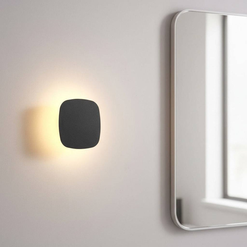 black vanity wall light mounted next to a bathroom mirror on the wall 