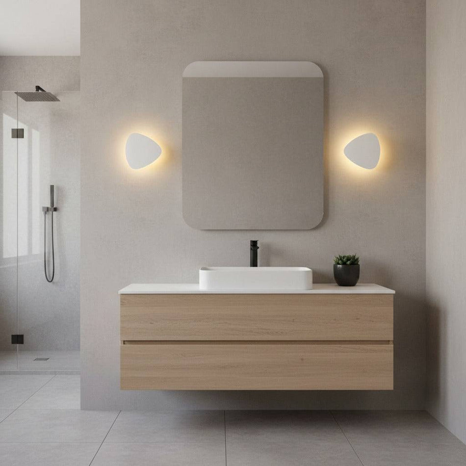 white wall mounted vanity light mounted either side of the mirror in a modern bathroom 
