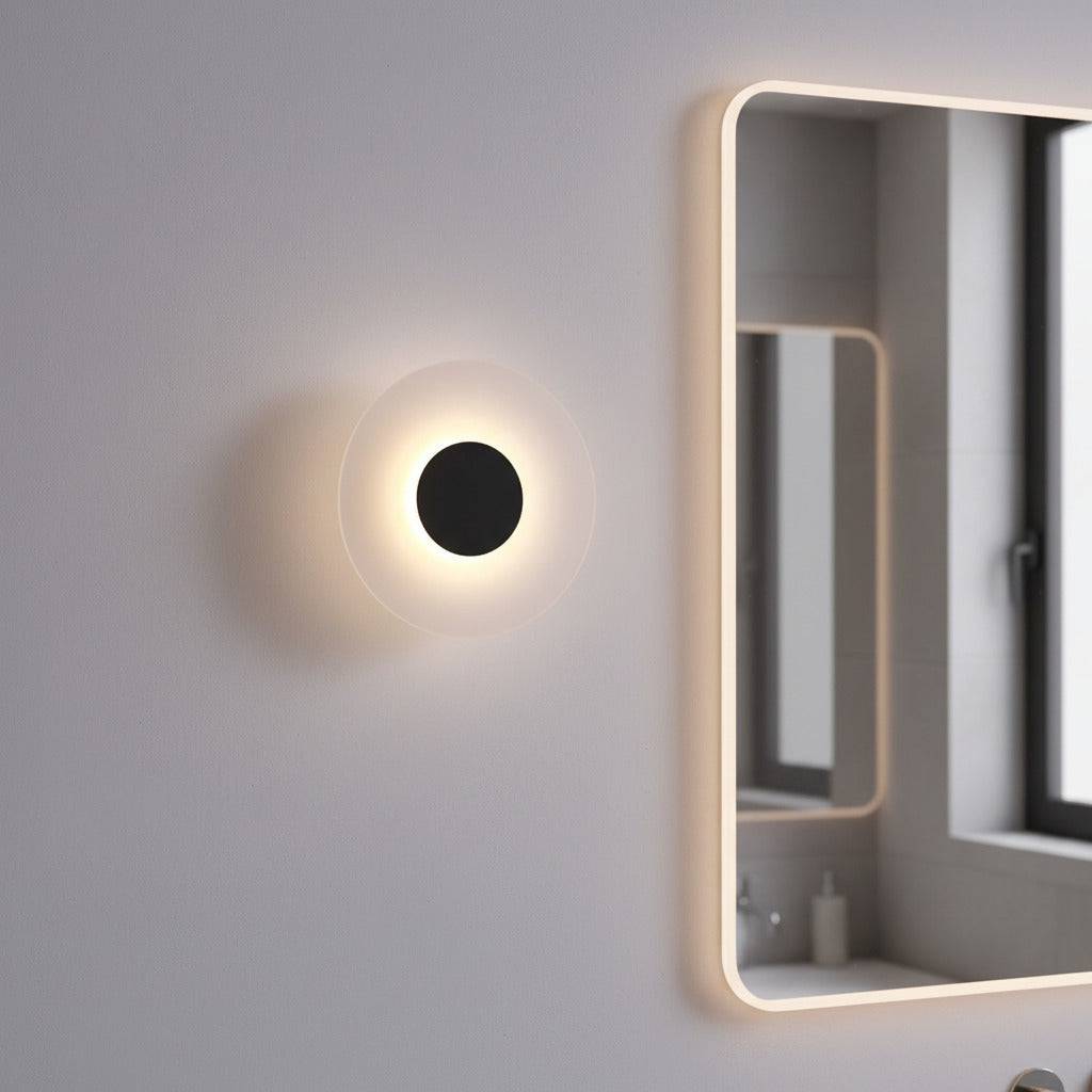 black bath sconce light mounted on the wall next to a bathroom mirror