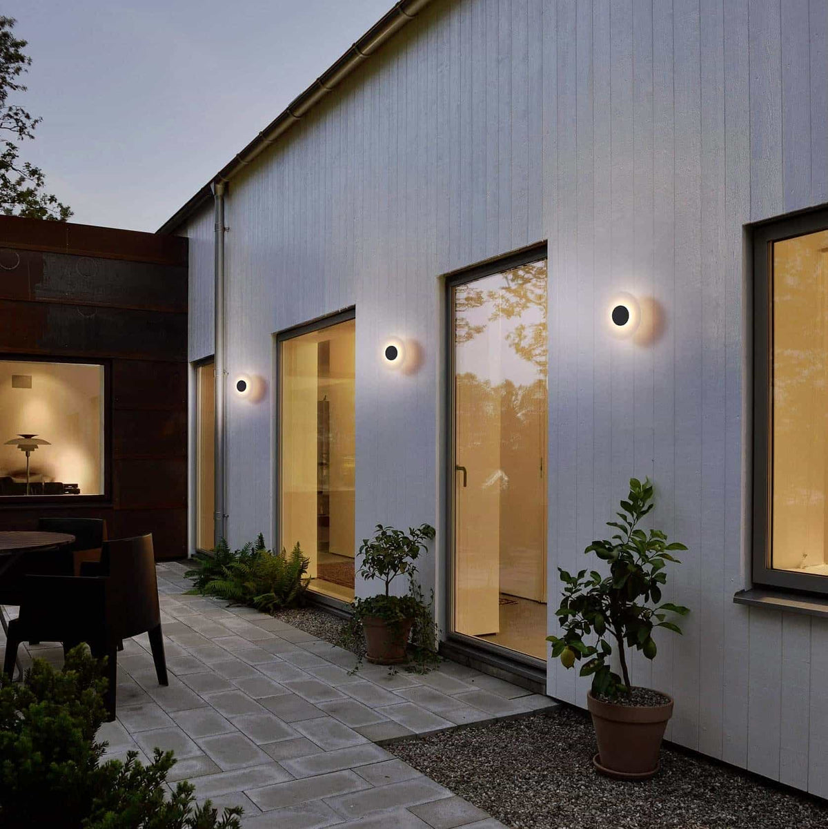 black wall outdoor lamp mounted in a line along and exterior wall at the back of a modern home