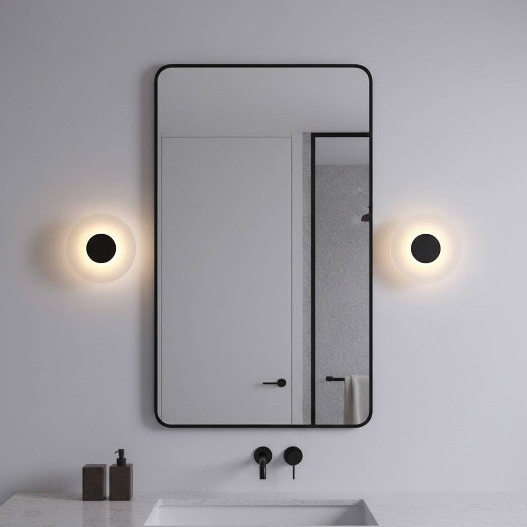 black bath sconce light mounted either side of a mirror in a bathroom 