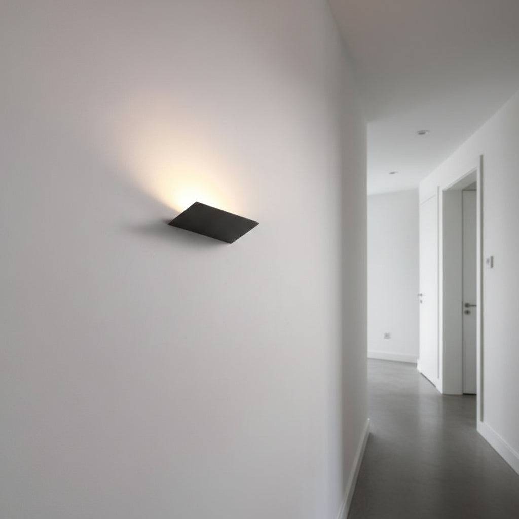 Black internal wall uplighter on a grey wall in a hallway of a modern home
