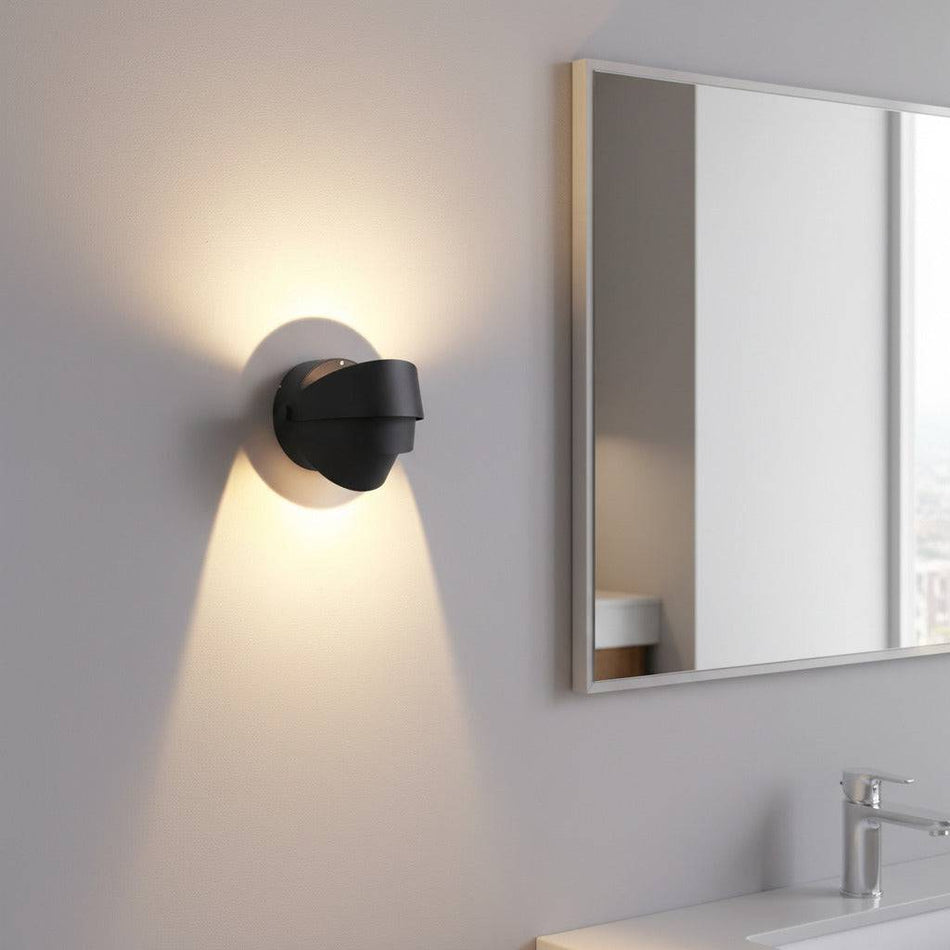 black vanity sconce light mounted on the wall in a modern bathroom next to the mirror 
