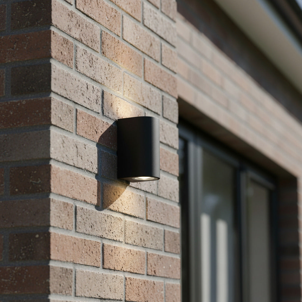 black outdoor up down light installed on a brick wall 