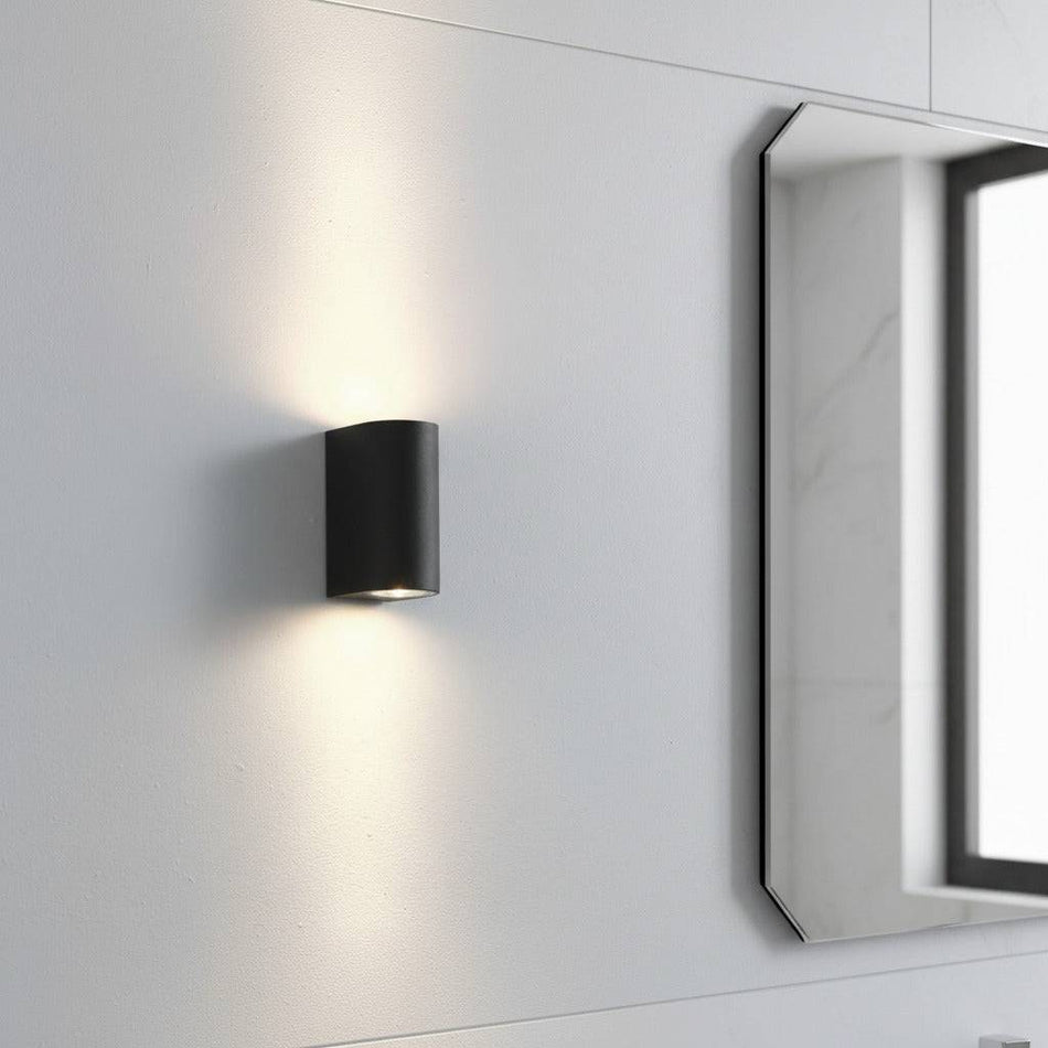 black bathroom wall mount light fitting shown on a wall next to a mirror in a bathroom