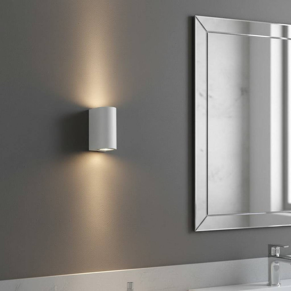 white contemporary sconce for bathroom mounted next to a bathroom mirror 