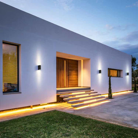 black outdoor up down light mounted in a row on the wall outside a modern home 