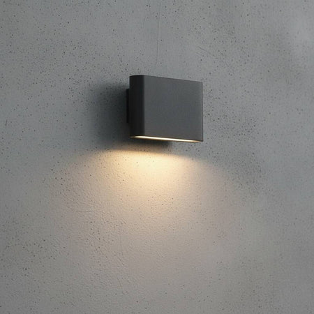 Black outdoor LED wall downlight mounted on a grey concrete exterior wall 