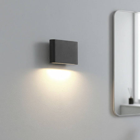 black LED bathroom sconce light mounted in a modern bathroom on the wall next to a mirror 