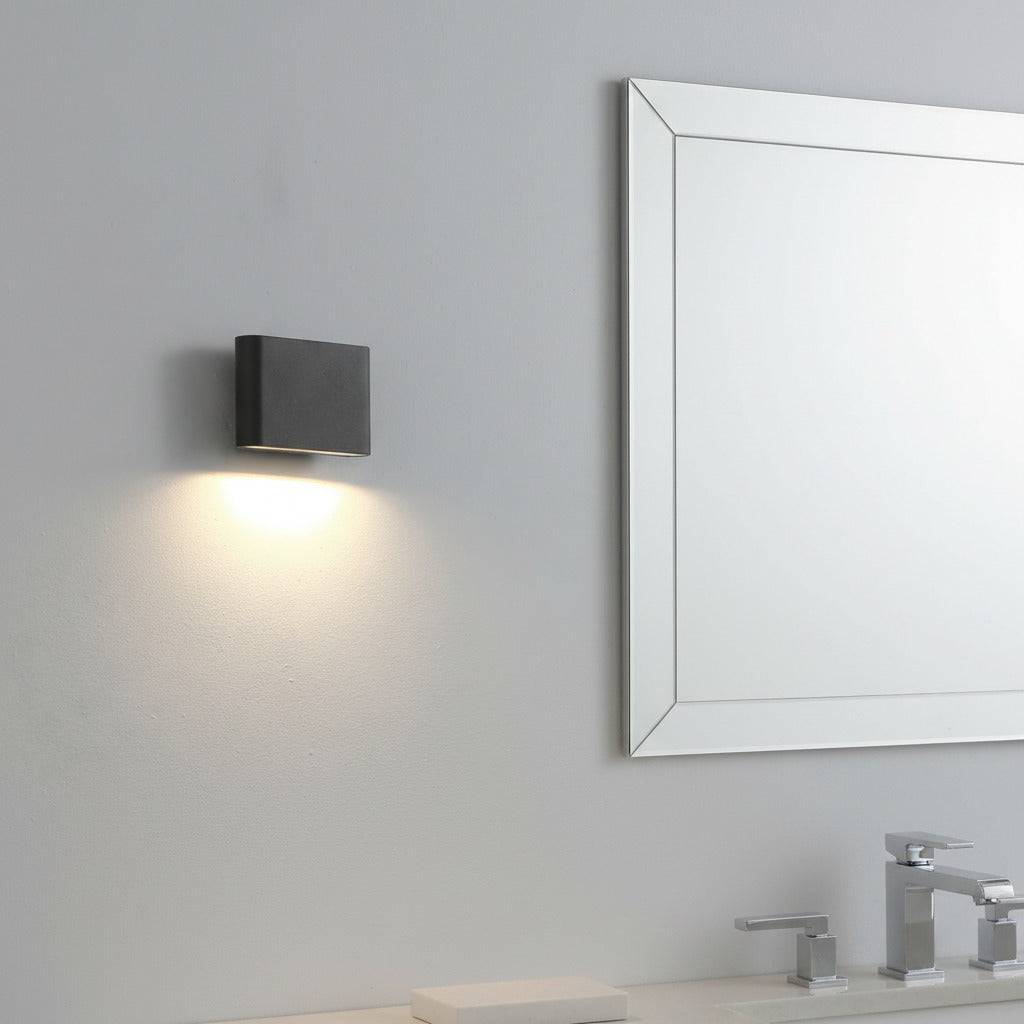 black LED bathroom sconce mounted on the wall of a bathroom next to a mirror 
