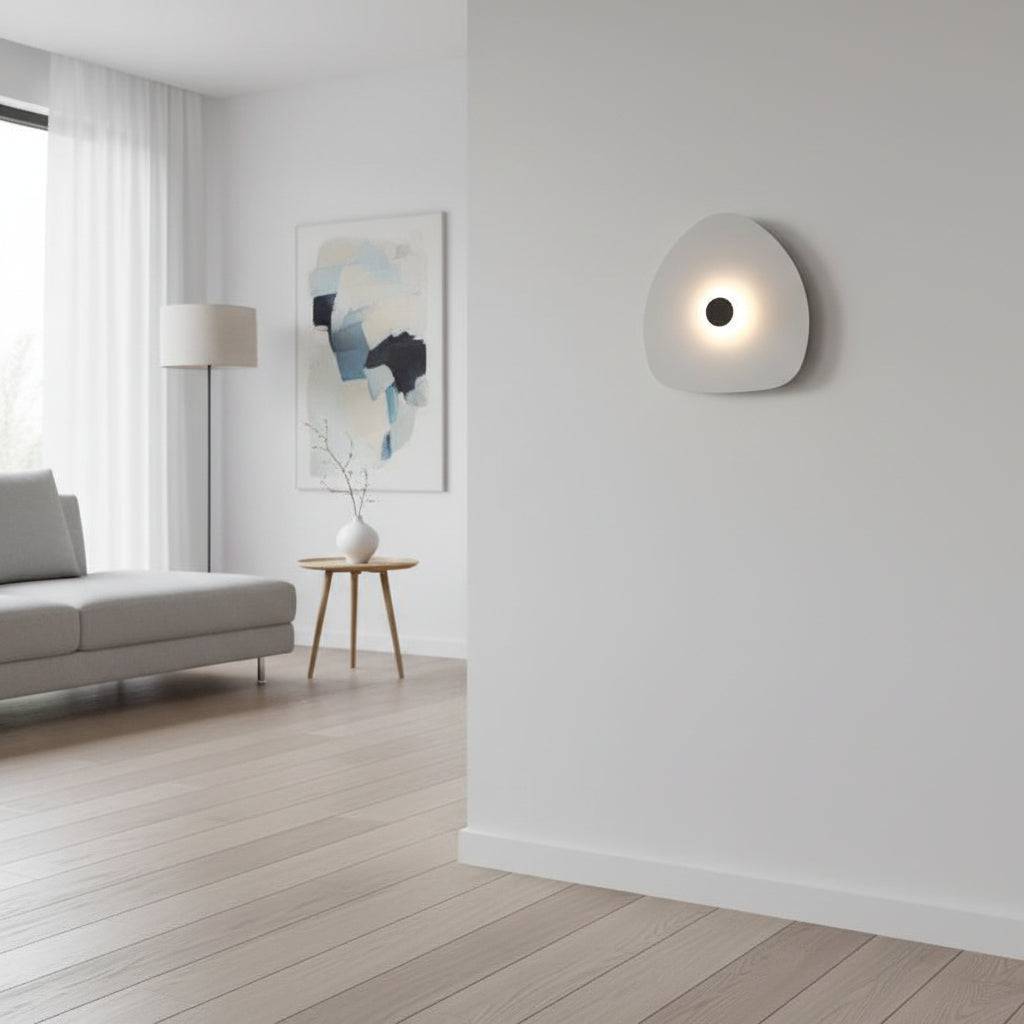 Modern internal wall light with a white finish and a black central halo on a wall within  a modern lounge