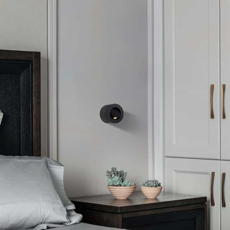 black bedside light for reading installed next to the bed on the wall in a modern bedroom