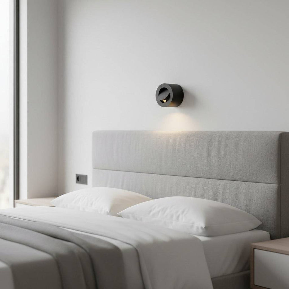 black bedside light for reading mounted on the wall over a bed in a modern minimal bedroom