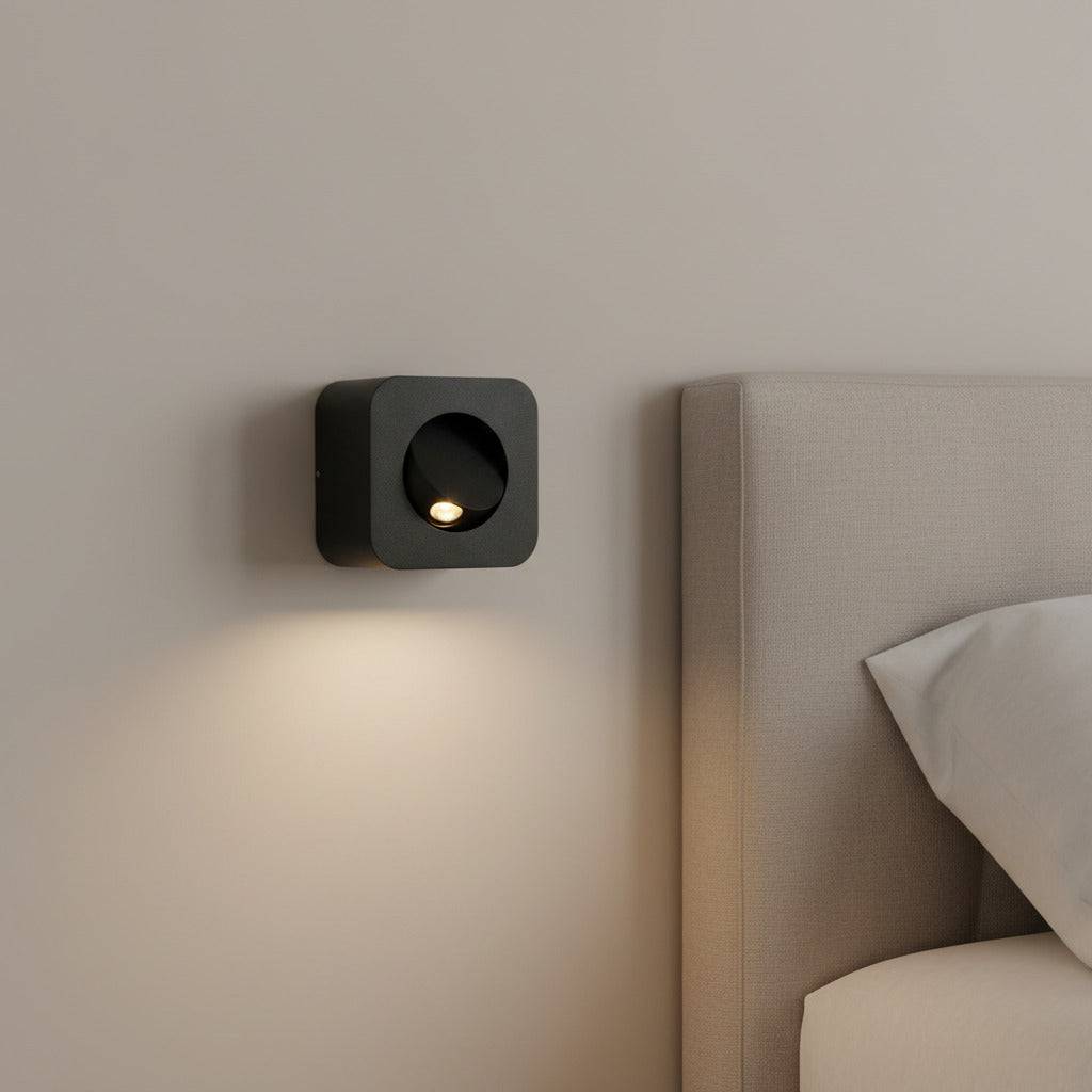 black surface mounted bedroom wall reading light mounted next to the bed in a modern bedroom. 