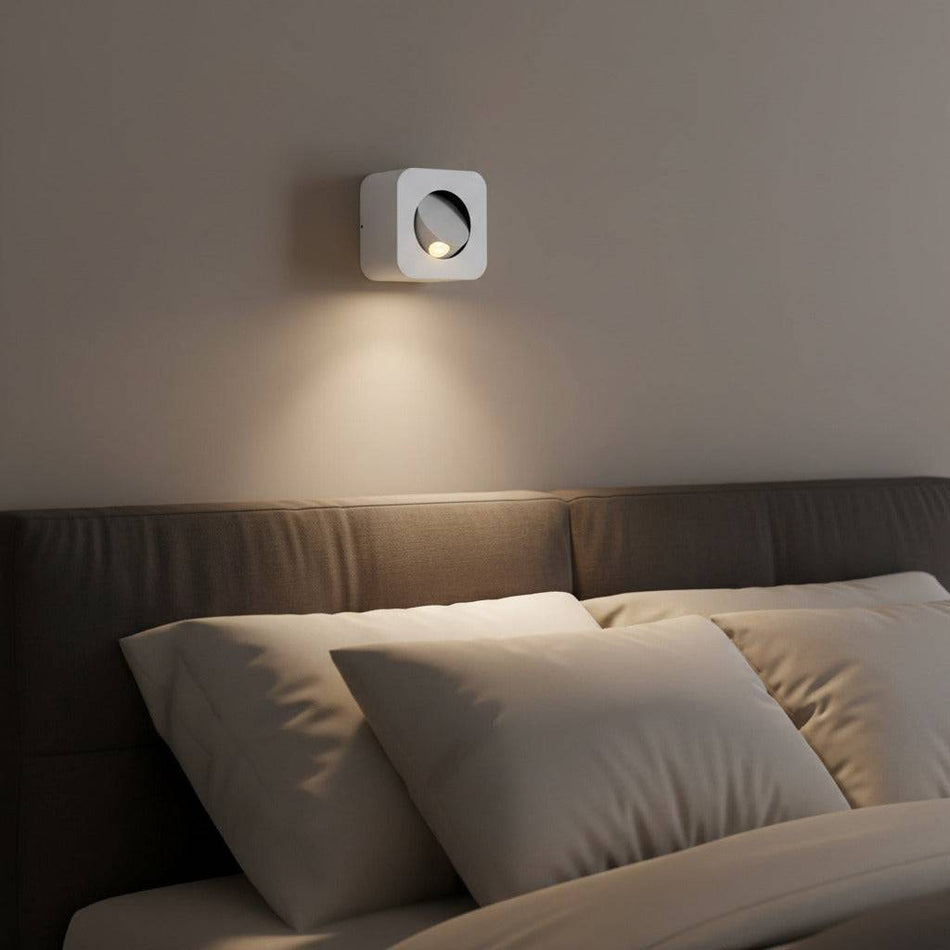 white wall mounted bedside lamp mounted on a wall above a bed in a modern bedroom