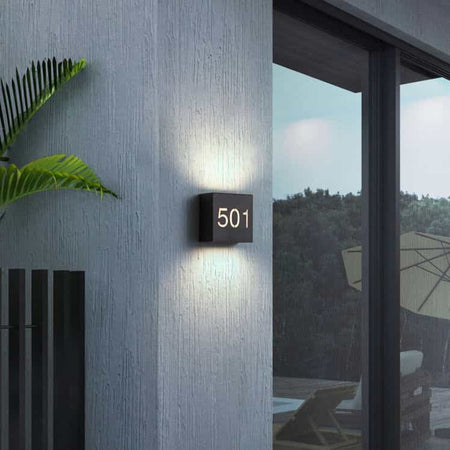 black backlit house number side installed on the wall outside a modern home
