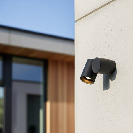 black outside spotlight wall light mounted on a concrete wall outside a modern house