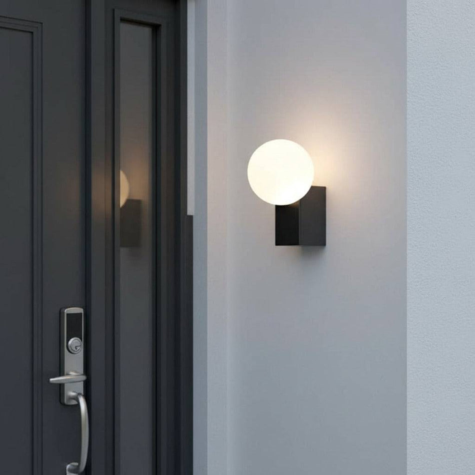 black outdoor wall globe light mounted on a white wall next to the entrance door of a house
