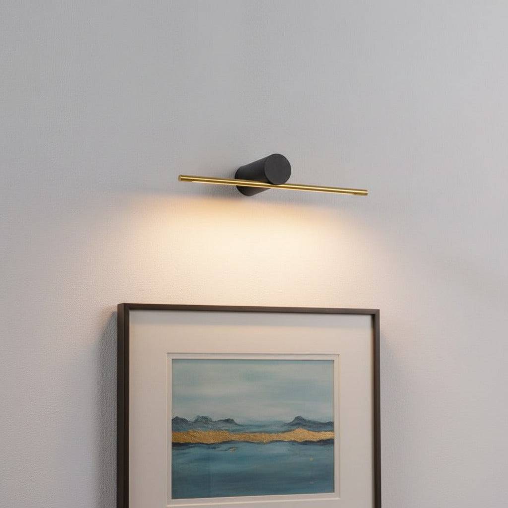 gold picture light mounted on the wall over artwork 