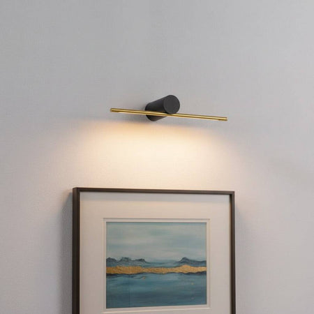 gold picture light mounted on the wall over artwork 