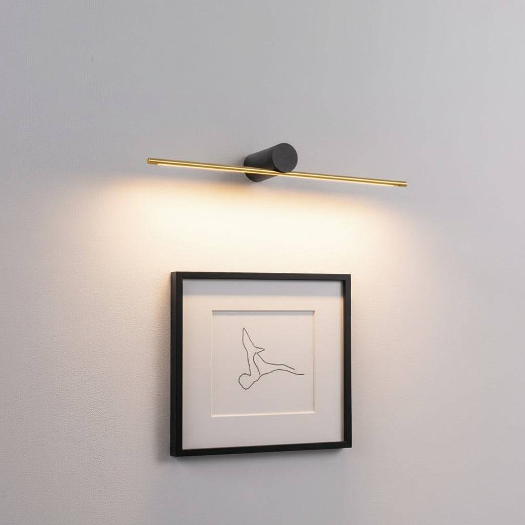 gold picture light fixture mounted on the wall over some modern artwork 