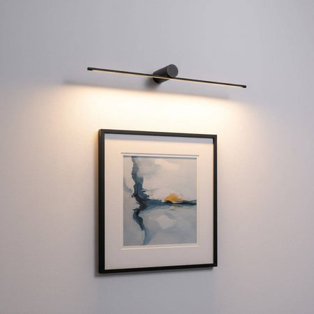 black above picture light mounted on the wall over some artwork 