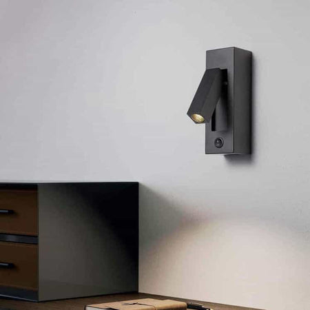 black wall mounted reading lamp mounted on the wall over a desk 