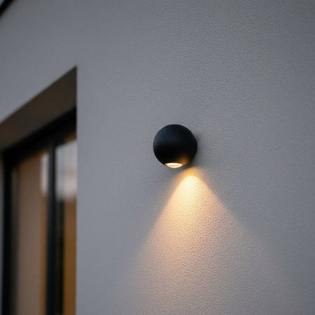 black outdoor downlight wall light mounted on a white exterior wall next to a home front door 