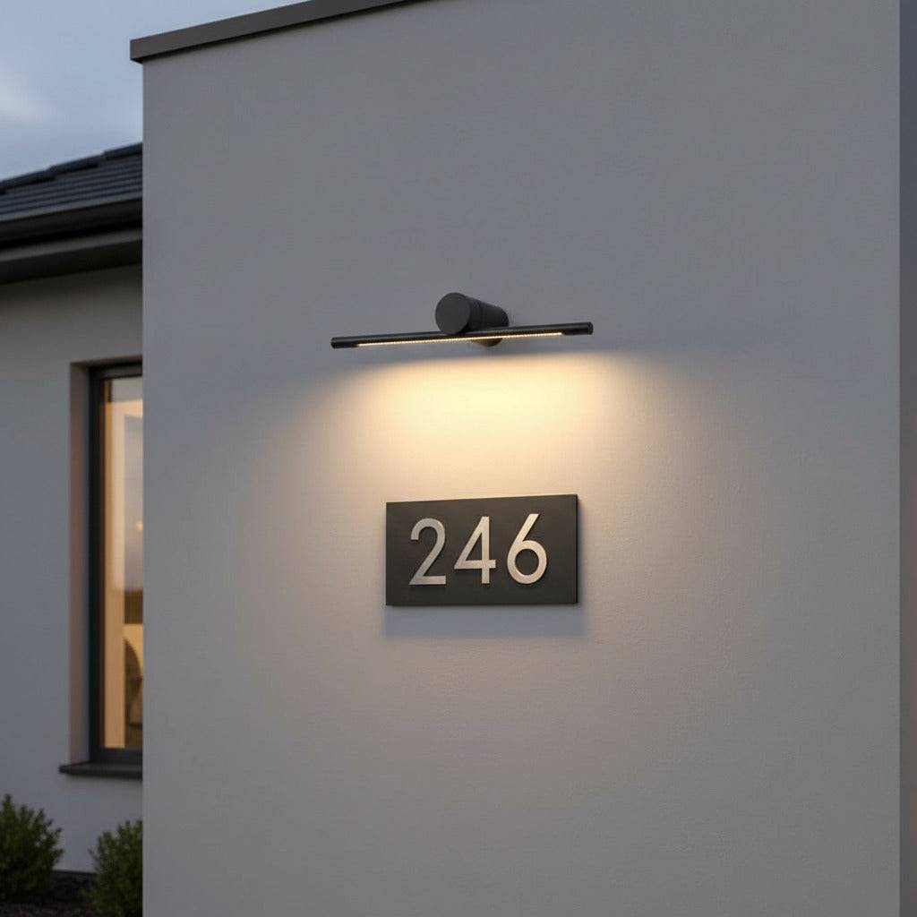 black sign wall light mounted over a house number on the wall of a modern house 