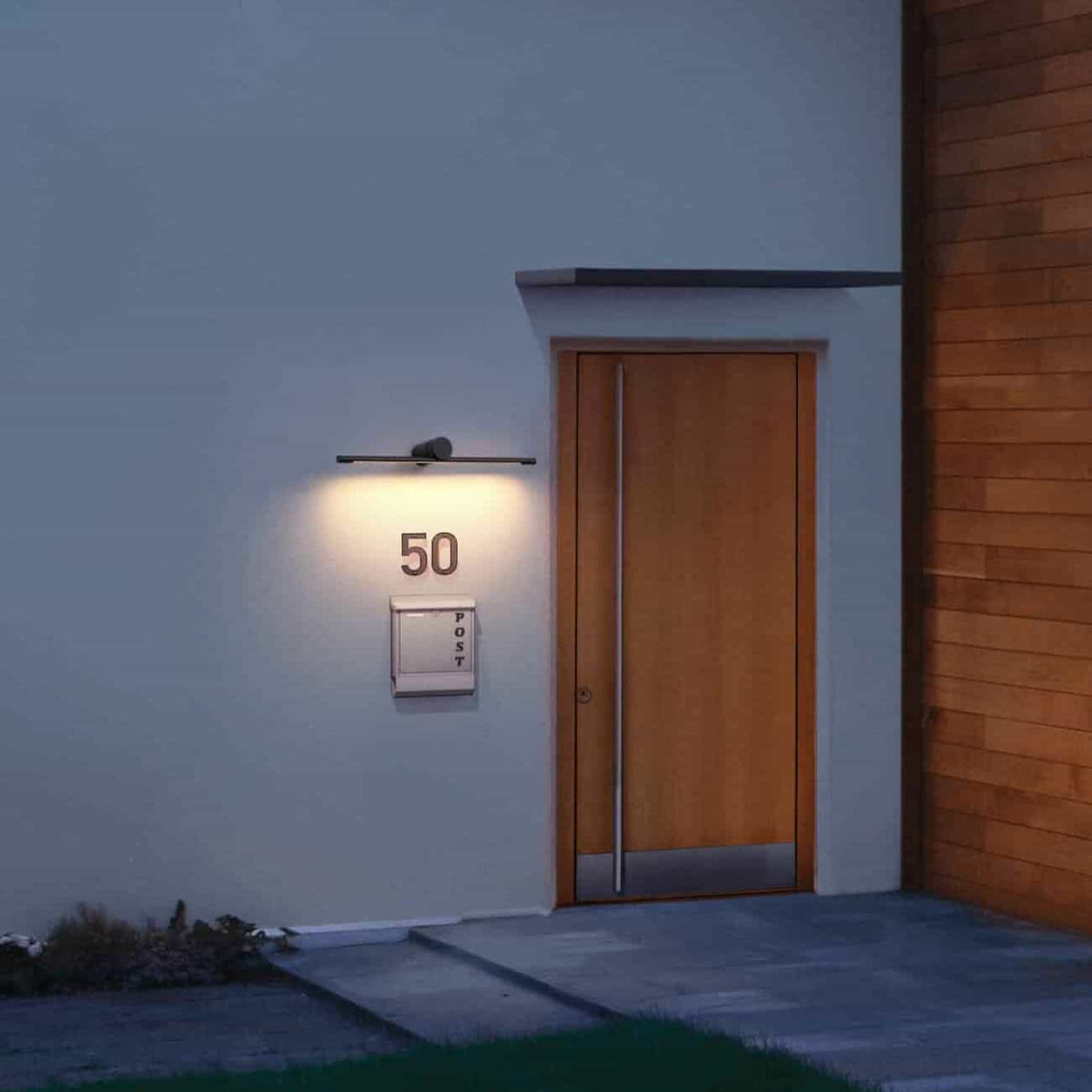 black over sign light mounted over a house number next to a house front door