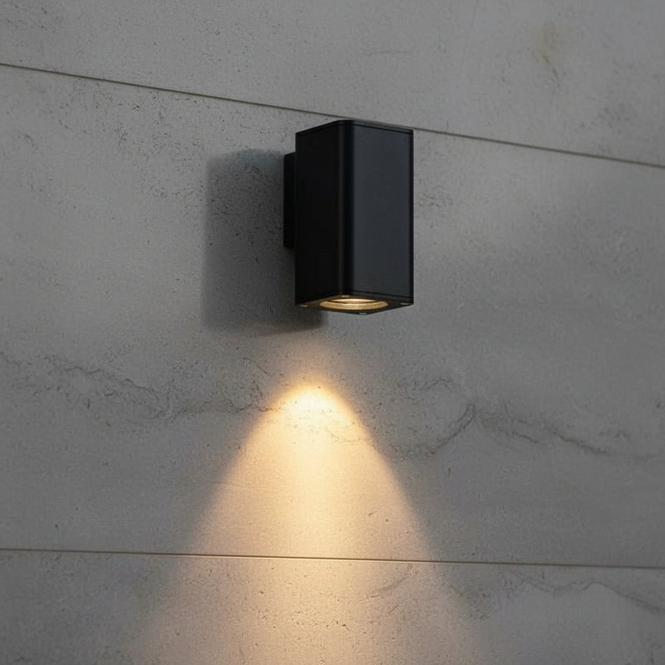 black outdoor wall downlighter mounted on a textured exterior wall 