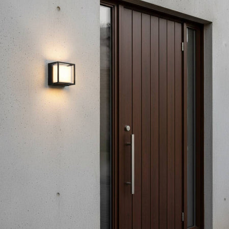 black square outside wall light mounted on a white wall next to a wooden front door
