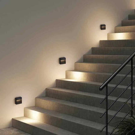black outdoor low level wall light mounted on the wall alongside steps